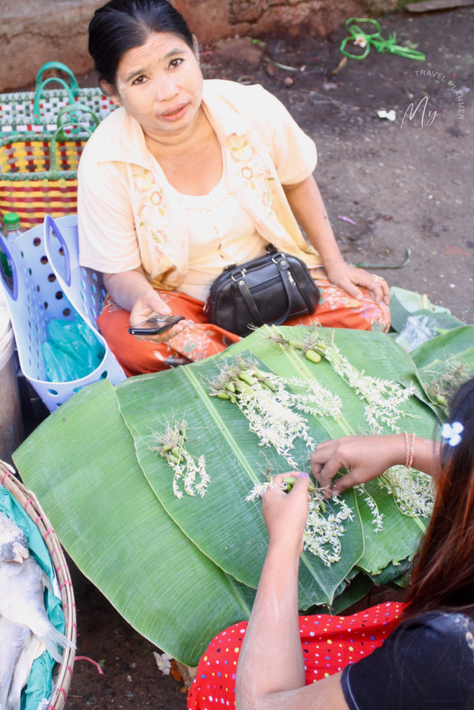 Donna birmana che prepara fili di fiori per la preghiera al mercato del mattino di Yangon
